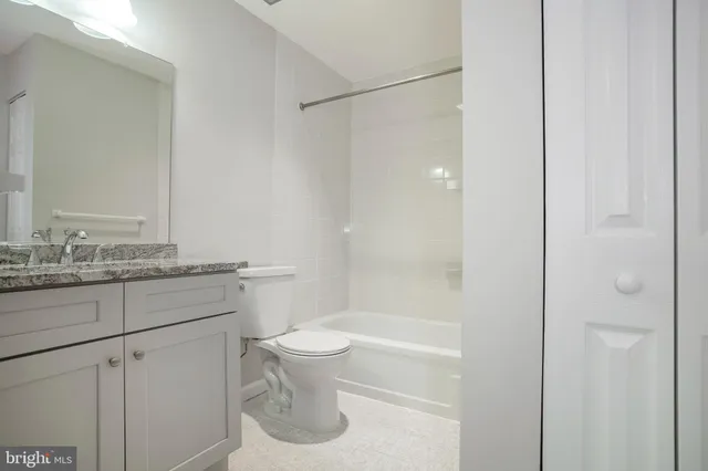 a bathroom with a granite countertop sink a toilet and shower