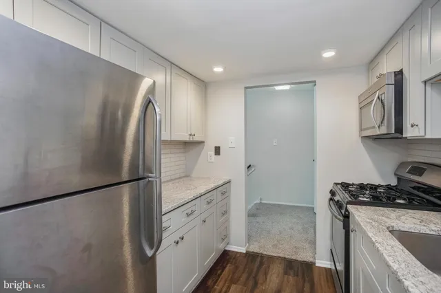 a kitchen with stainless steel appliances granite countertop a refrigerator a stove and a sink with wooden floor