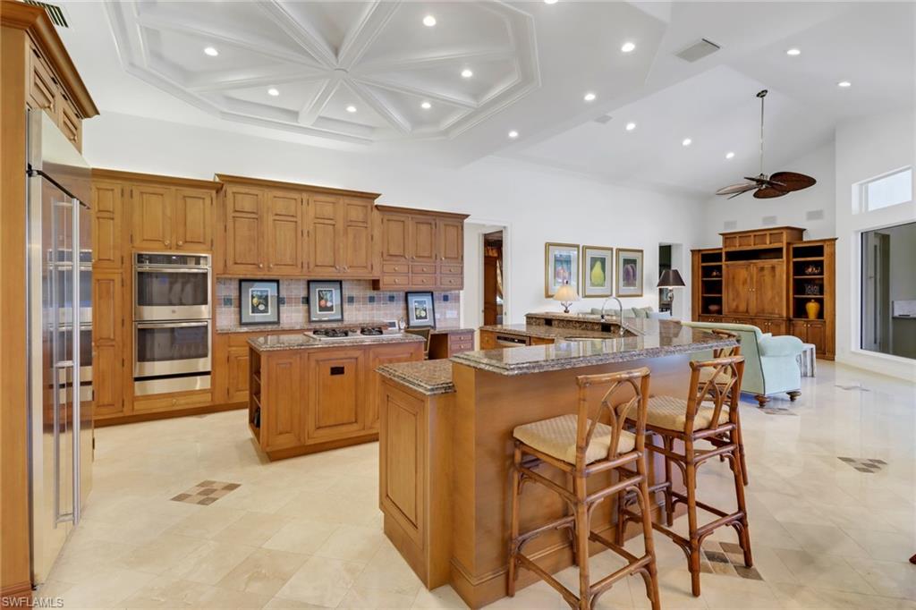 9376 Sweetgrass Way Naples, FL 34108 - Photo 12 of 49 a kitchen with stainless steel appliances kitchen island granite countertop a table chairs sink and cabinets