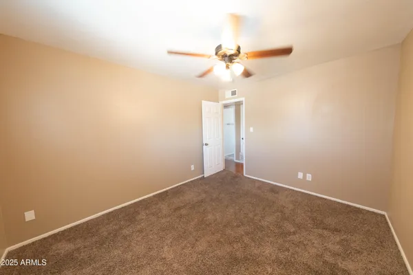 an empty room with a window and a ceiling fan