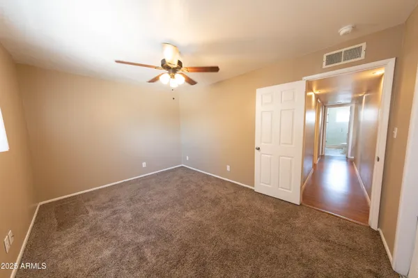 an empty room with closet and a chandelier fan