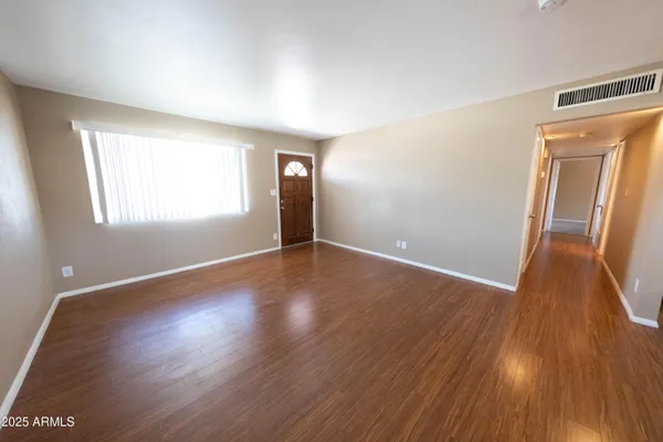 a view of an empty room with wooden floor and a window