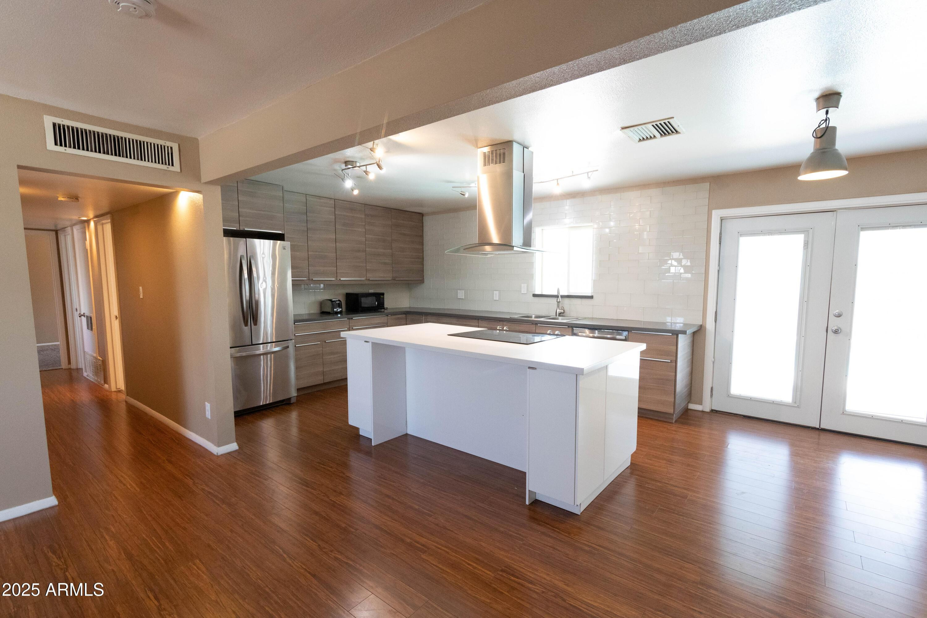 1149 West 10th Street Tempe, AZ 85281 - Photo 5 of 19 a large kitchen with a center island wooden floor stainless steel appliances and windows