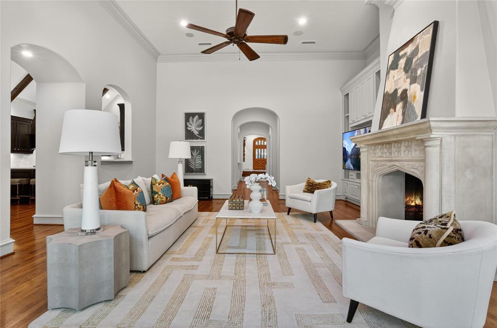 11836 Preston Brook Place Dallas, TX 75230 - Photo 13 of 40 Living room with arched walkways, a high end fireplace, light wood-style flooring, ornamental molding, and a ceiling fan