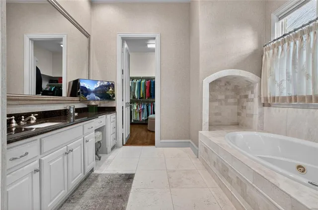 a spacious bathroom with a tub sink and mirror