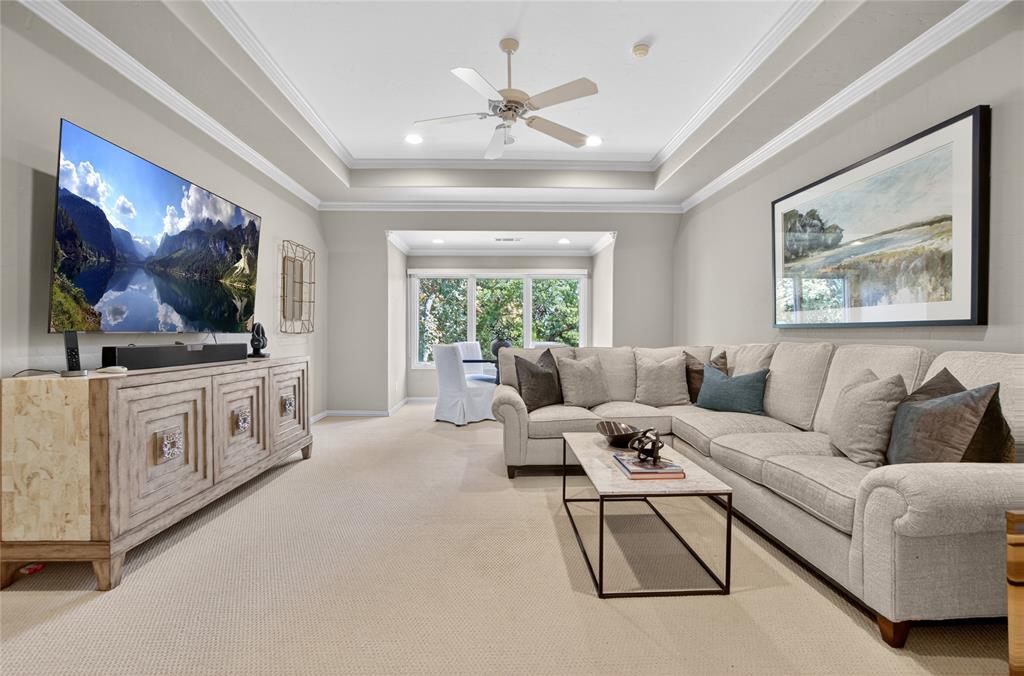 11836 Preston Brook Place Dallas, TX 75230 - Photo 29 of 40 Carpeted living room featuring a raised ceiling, ornamental molding, a ceiling fan, and recessed lighting