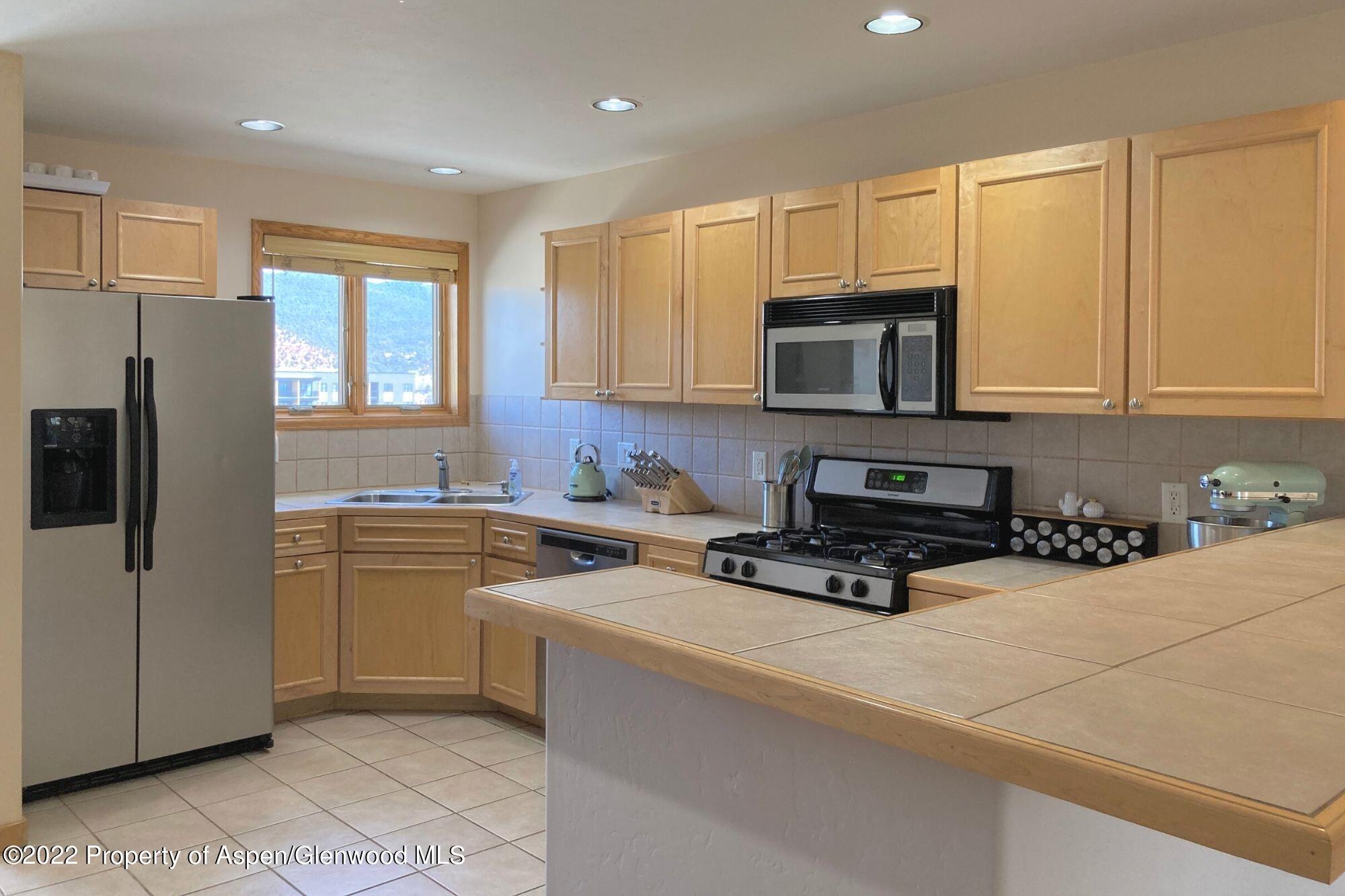 a kitchen with stainless steel appliances a stove a sink a refrigerator a microwave and cabinets