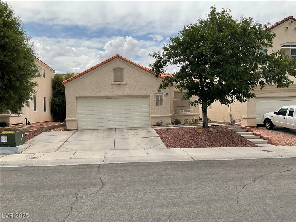 7620 Donald Nelson Avenue Las Vegas, NV 89131 - Photo 33 of 34 Mediterranean / spanish house featuring concrete driveway, an attached garage, and stucco siding