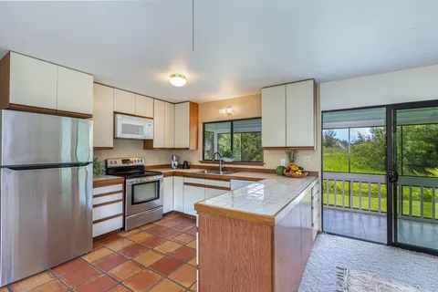 a kitchen with granite countertop a refrigerator a stove top oven a sink and a large window