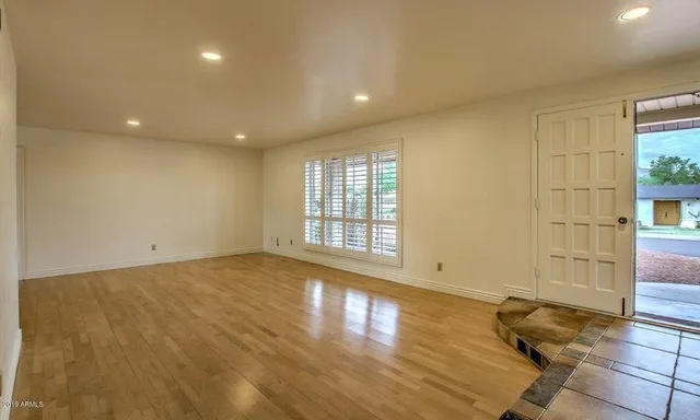 a view of empty room with wooden floor and fan