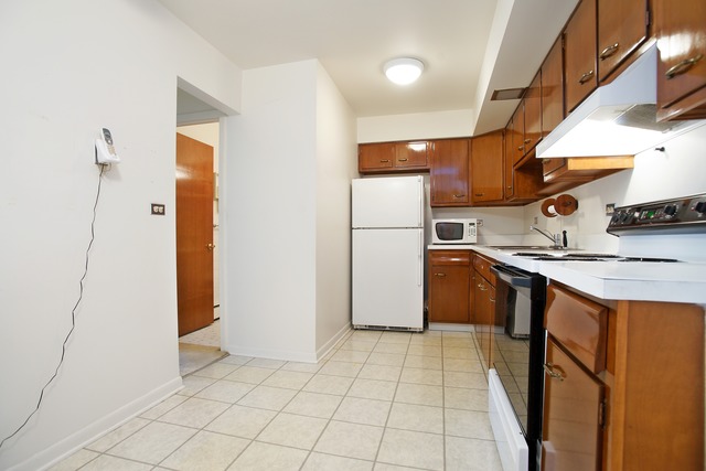 2222 South Goebbert Road, Unit 361 Arlington Heights, IL 60005 - Photo 3 of 10 a kitchen with kitchen island granite countertop a refrigerator a sink and white cabinets