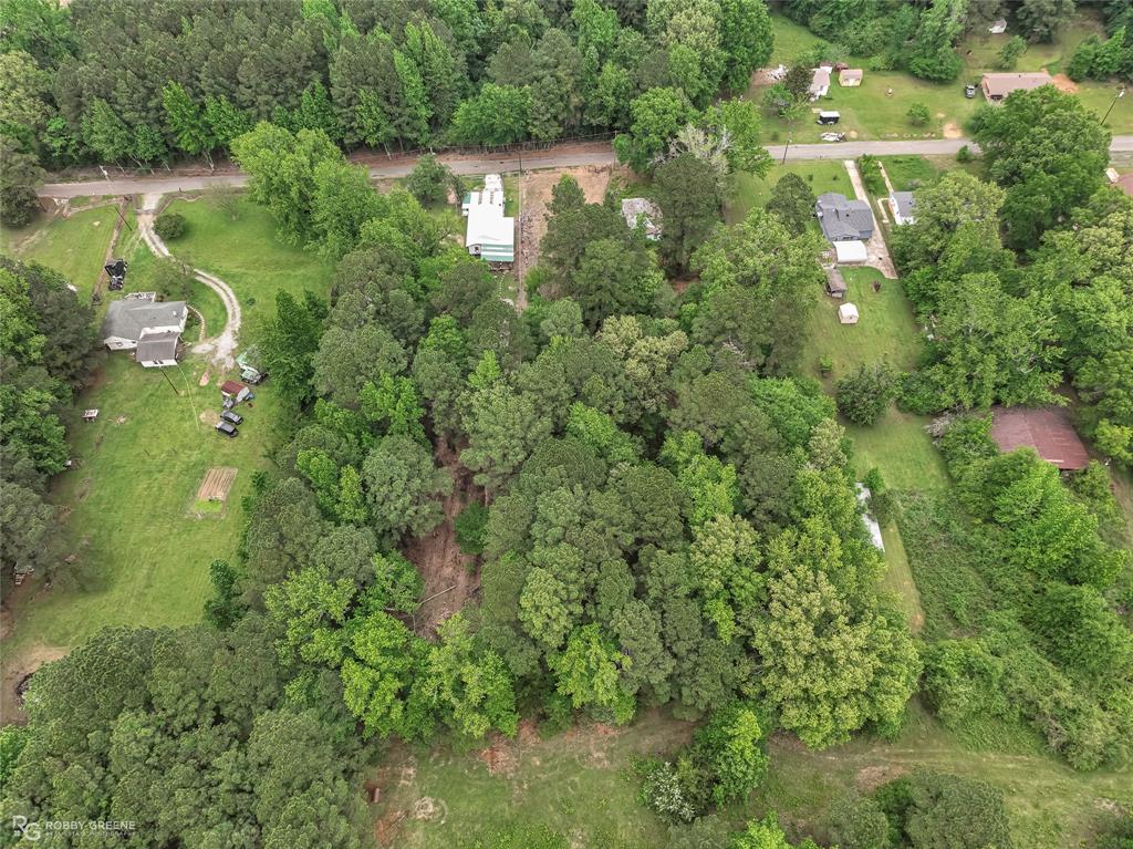143 New Bethel Booker Road Benton, LA 71006 - Photo 26 of 26 Expansive wooded parcel featuring a winding gravel driveway, a single-story residence with a dark roof, surrounding green spaces, and mature trees