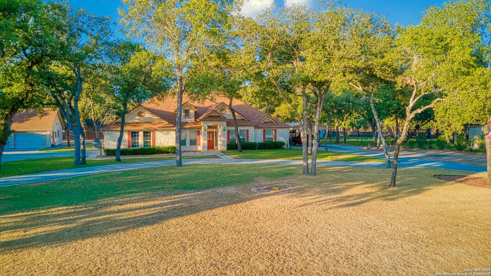 a view of a house with a big yard plants and large trees