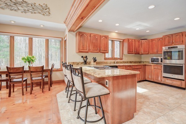 583 Sugar Road Bolton, MA 01740 - Photo 12 of 30 a kitchen with stainless steel appliances granite countertop a stove a sink a microwave a dining table and chairs with wooden floor