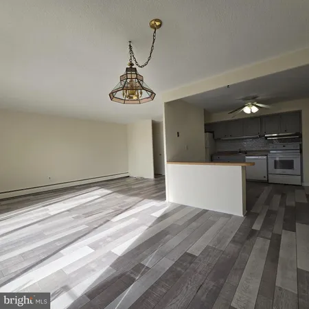 a view of a room with wooden floor and kitchen view