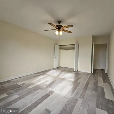 a view of a room with a ceiling fan and hardwood floor