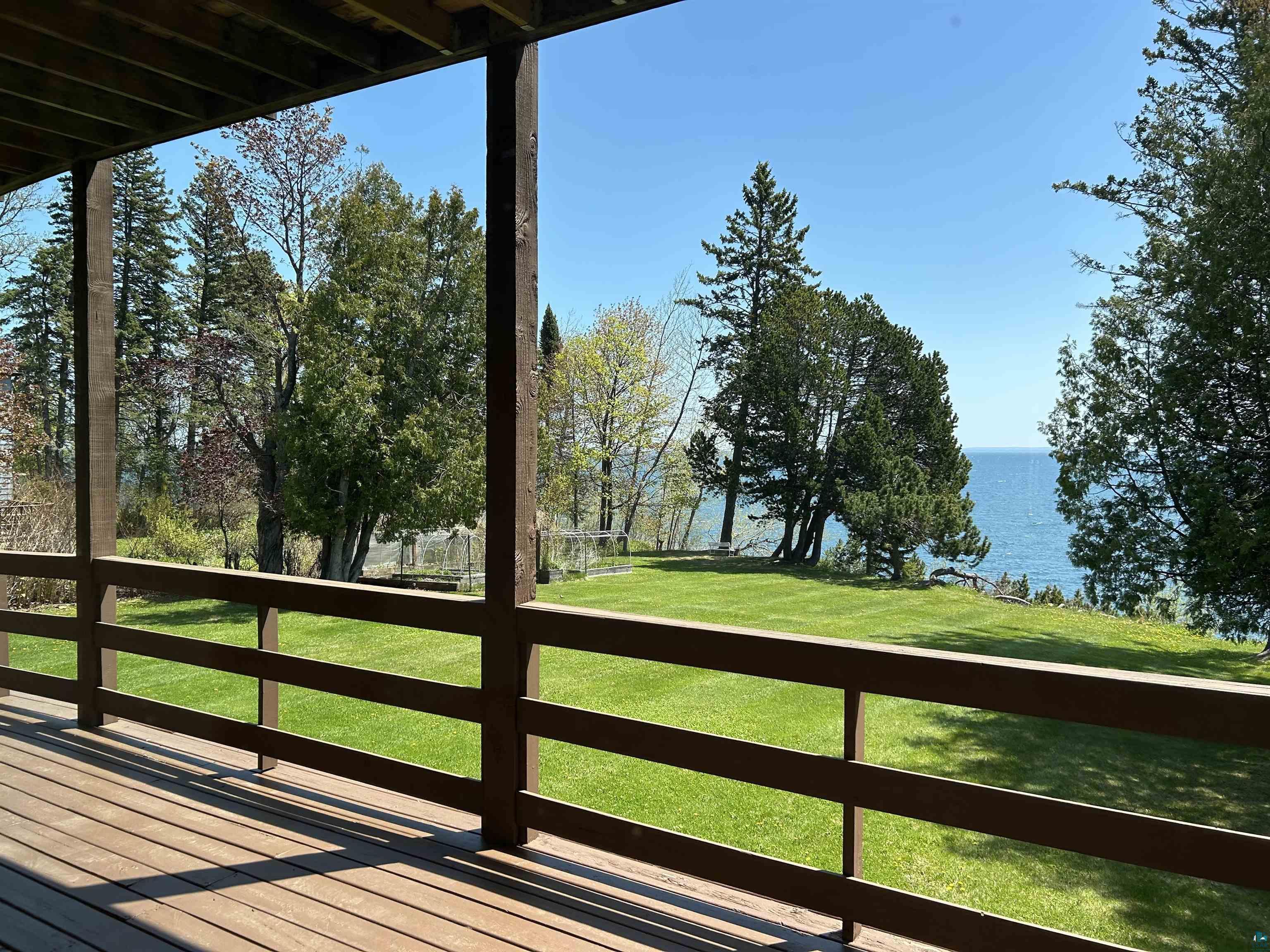 5090 London Road, Unit 1 Duluth, MN 55804 - Photo 26 of 54 Spacious wood-finish deck with a brown railing, overlooking a large grassy lawn and mature trees