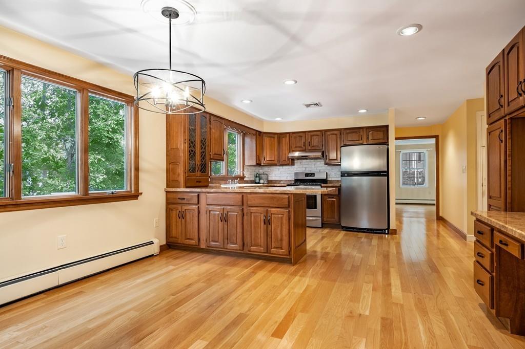 2 Alben Street Winchester, MA 01890 - Photo 12 of 33 a kitchen with stainless steel appliances granite countertop a refrigerator a sink dishwasher a stove and a dining table with wooden floor