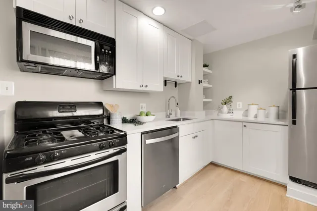 a kitchen with cabinets stainless steel appliances and wooden floor