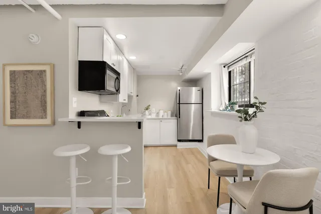 a kitchen with stainless steel appliances granite countertop a sink a stove a microwave a refrigerator and chairs