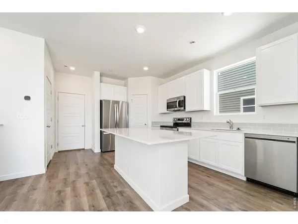 a kitchen with stainless steel appliances kitchen island sink refrigerator and microwave