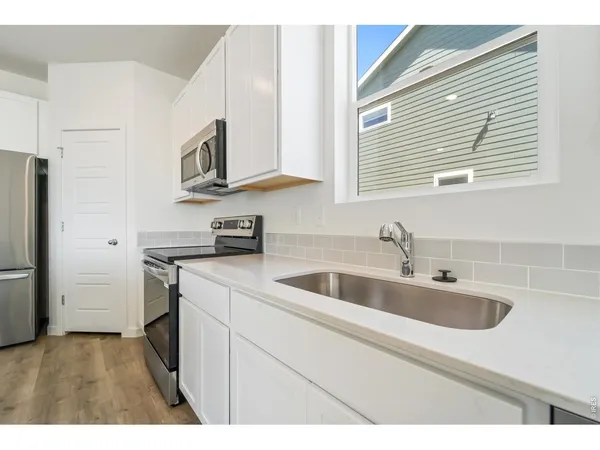 a kitchen with stainless steel appliances granite countertop a sink and a refrigerator