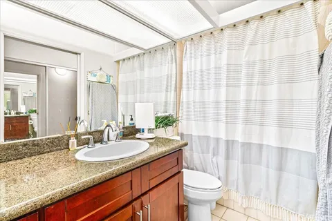 a bathroom with a granite countertop sink a toilet and a mirror