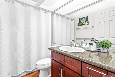 a bathroom with a granite countertop sink a toilet and a mirror
