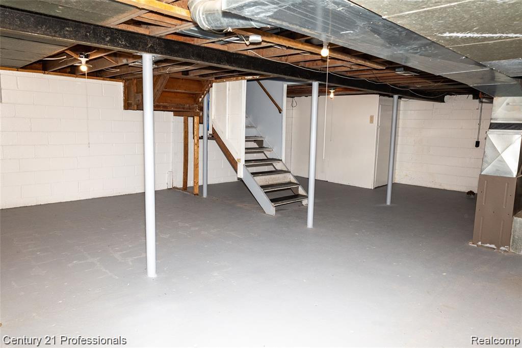 19372 Sunderland Road Detroit, MI 48219 - Photo 26 of 34 Spacious basement featuring painted concrete flooring, white block walls, exposed ceiling joists, and a utility staircase