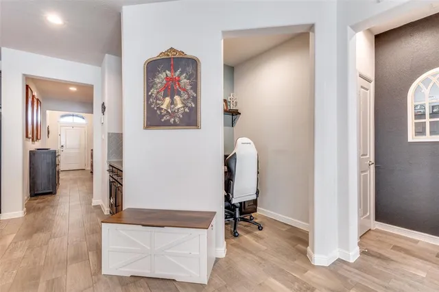 a view of a hallway with wooden floor and a bathroom