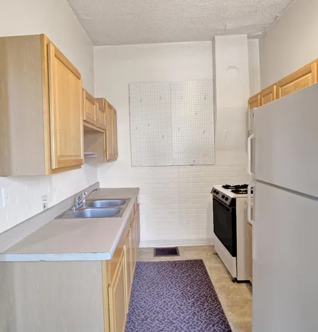 a kitchen with a sink a refrigerator and cabinets
