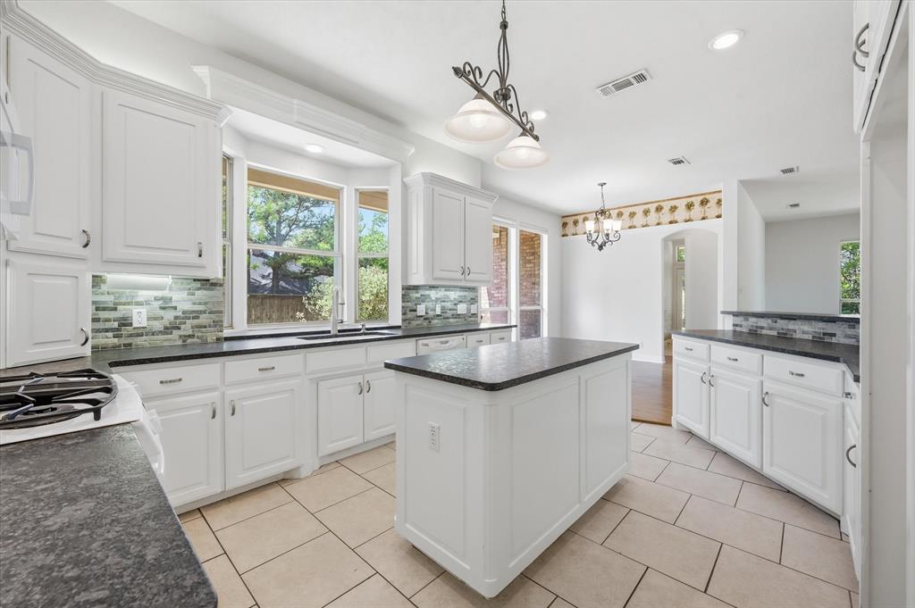 5513 Rustic Trail Colleyville, TX 76034 - Photo 16 of 40 a kitchen with granite countertop white cabinets white appliances a sink and a window