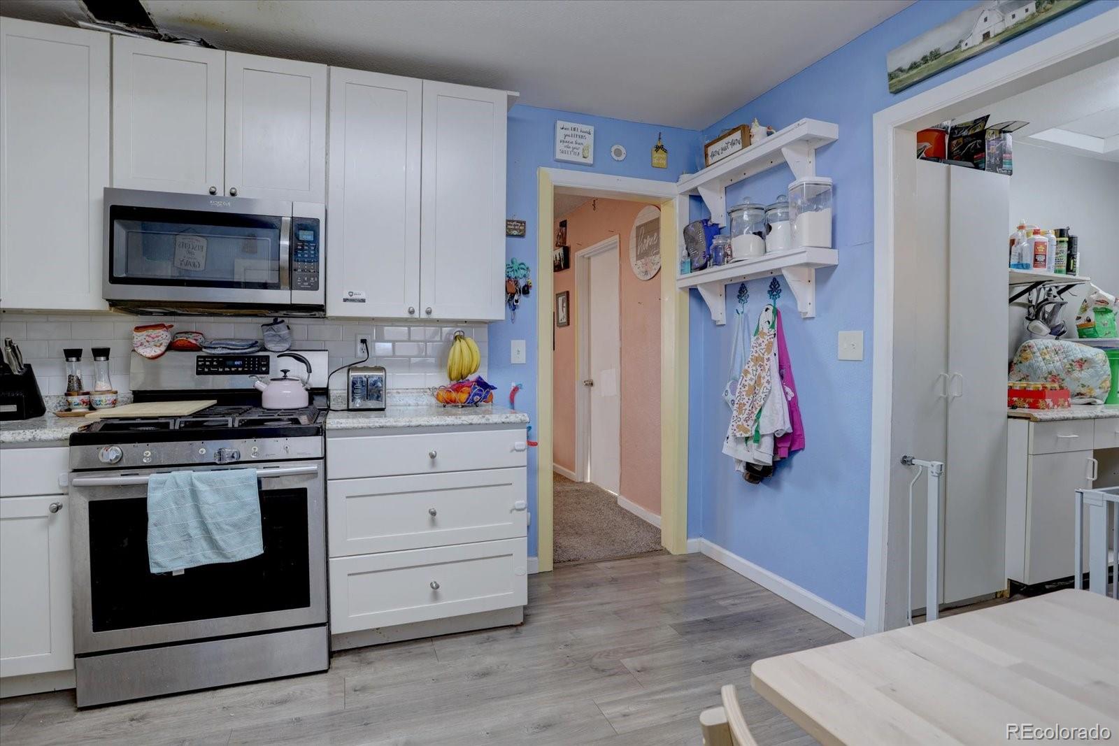 775 Victor Street Aurora, CO 80011 - Photo 7 of 21 a kitchen with stainless steel appliances white cabinets and a stove top oven