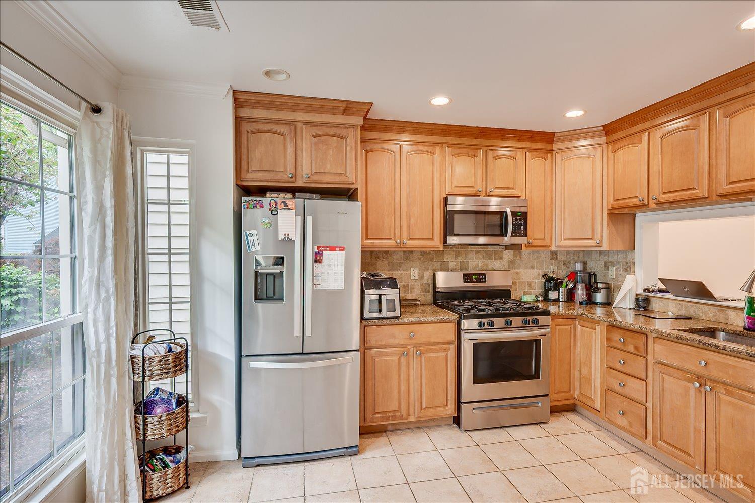 903 Maplecrest Road Edison, NJ 08820 - Photo 2 of 24 a kitchen with stainless steel appliances granite countertop a stove top oven a refrigerator and white cabinets with wooden floors