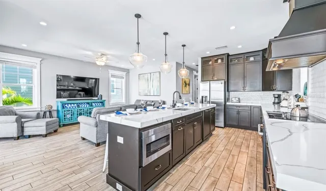 a large kitchen with stainless steel appliances kitchen island granite countertop a sink and a wooden floor