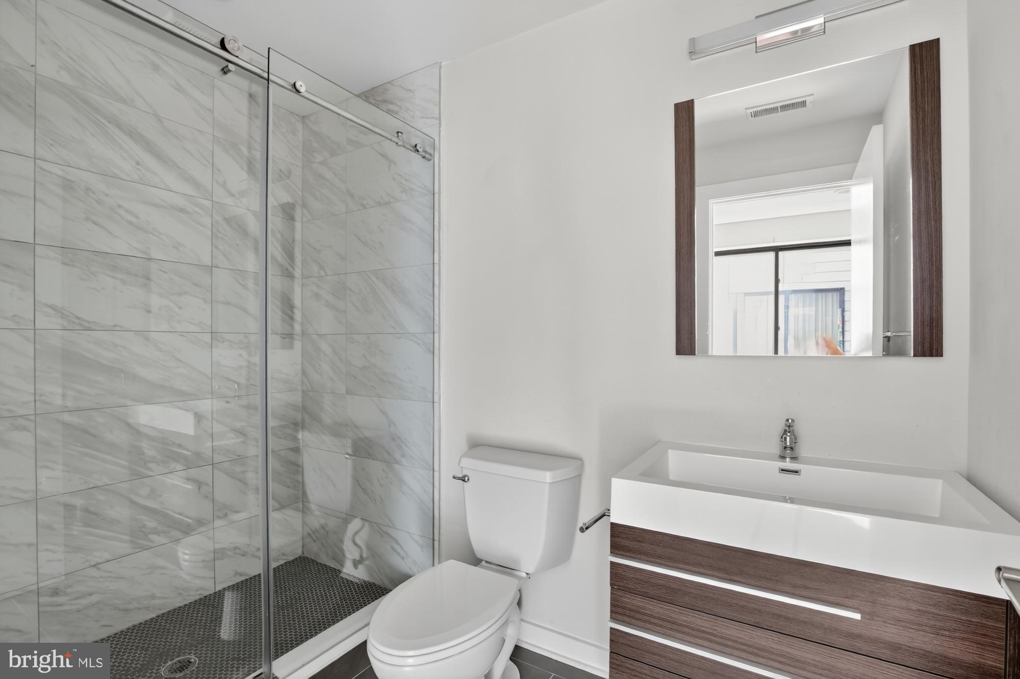 381 Martin Street, Unit 2 Philadelphia, PA 19128 - Photo 15 of 20 a bathroom with a sink a toilet and shower