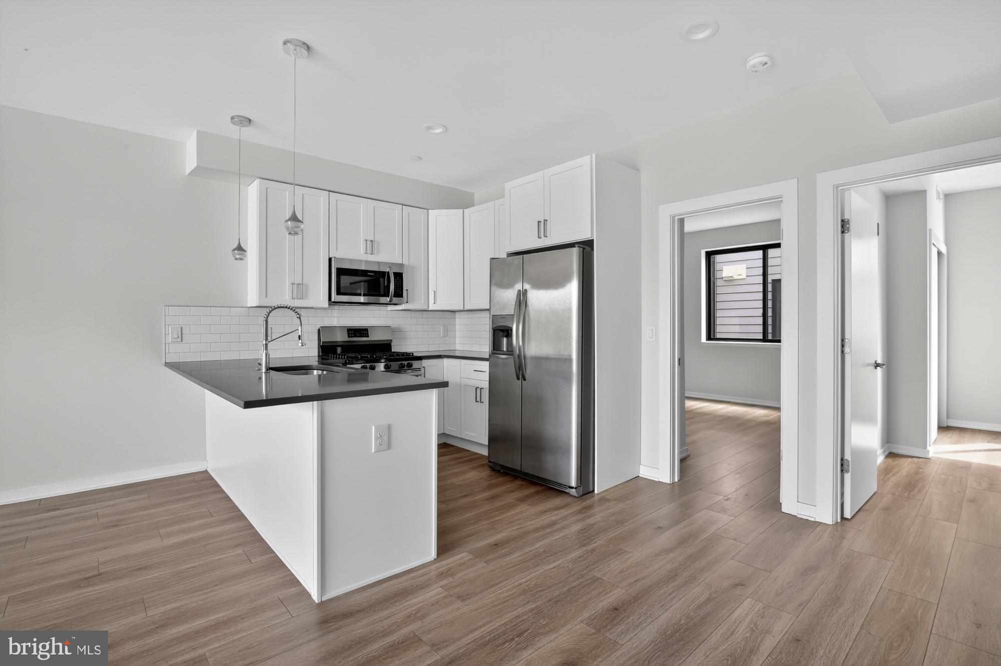 381 Martin Street, Unit 2 Philadelphia, PA 19128 - Photo 4 of 20 a kitchen with granite countertop a refrigerator and a stove top oven
