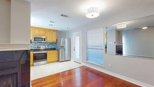 a kitchen with granite countertop a refrigerator a sink dishwasher a stove and white cabinets with wooden floor