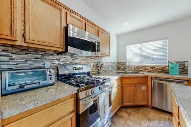 a kitchen with stainless steel appliances granite countertop a stove a sink and a microwave