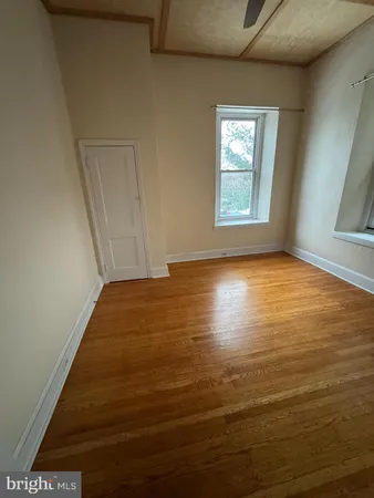 an empty room with wooden floor fan and windows