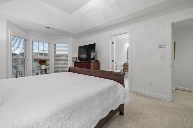 a bedroom with a large bed a flat tv screen and a night stand