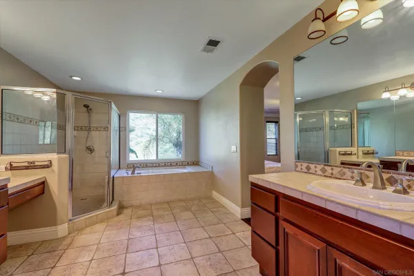 a spacious bathroom with a double vanity sink a mirror and a bathtub