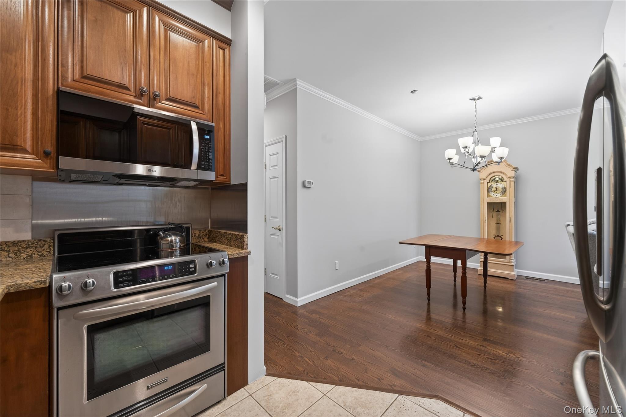 294 Spring Drive East Meadow, NY 11554 - Photo 9 of 31 Kitchen featuring stainless steel appliances, a chandelier, crown molding, dark tile patterned flooring, and decorative backsplash