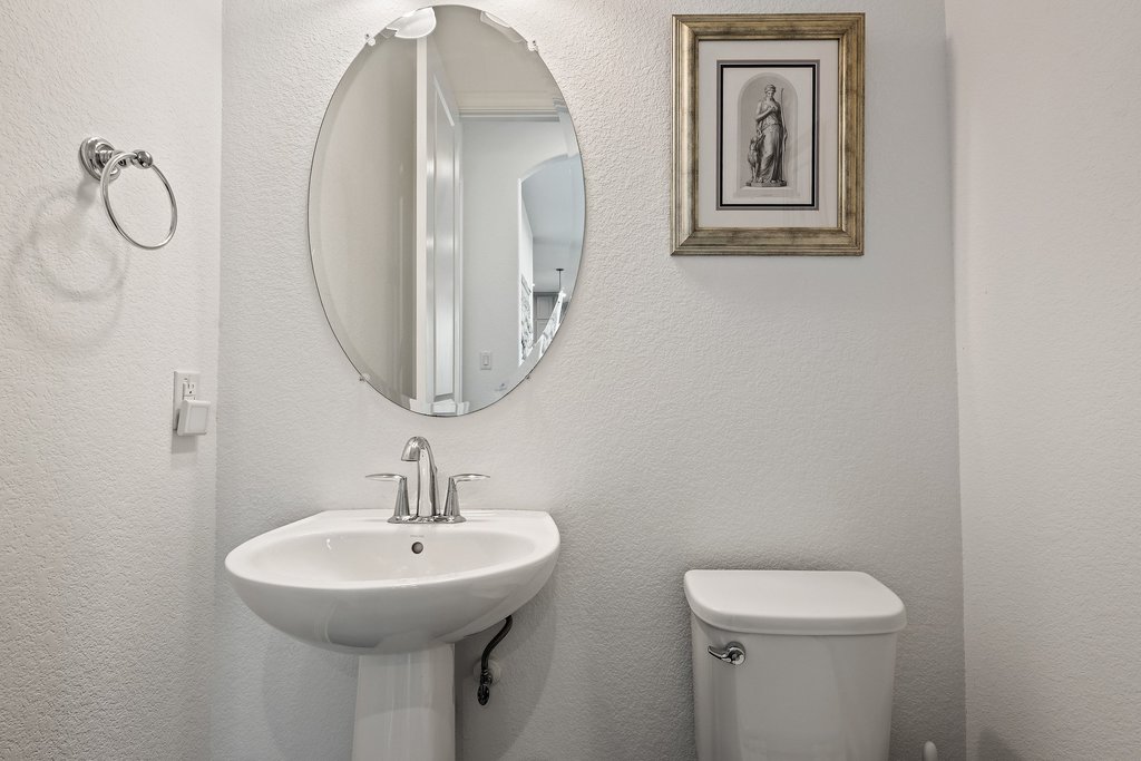 1221 Siena Sunset Road Leander, TX 78641 - Photo 34 of 39 Pedestal sink with chrome faucet, complemented by an oval beveled mirror