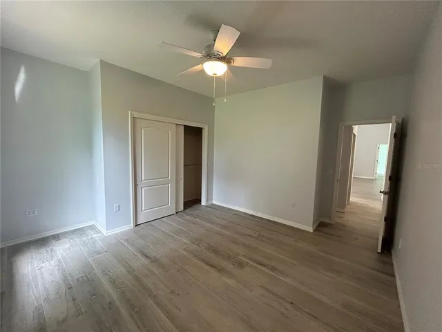 a view of an empty room and wooden floor and a chandelier fan
