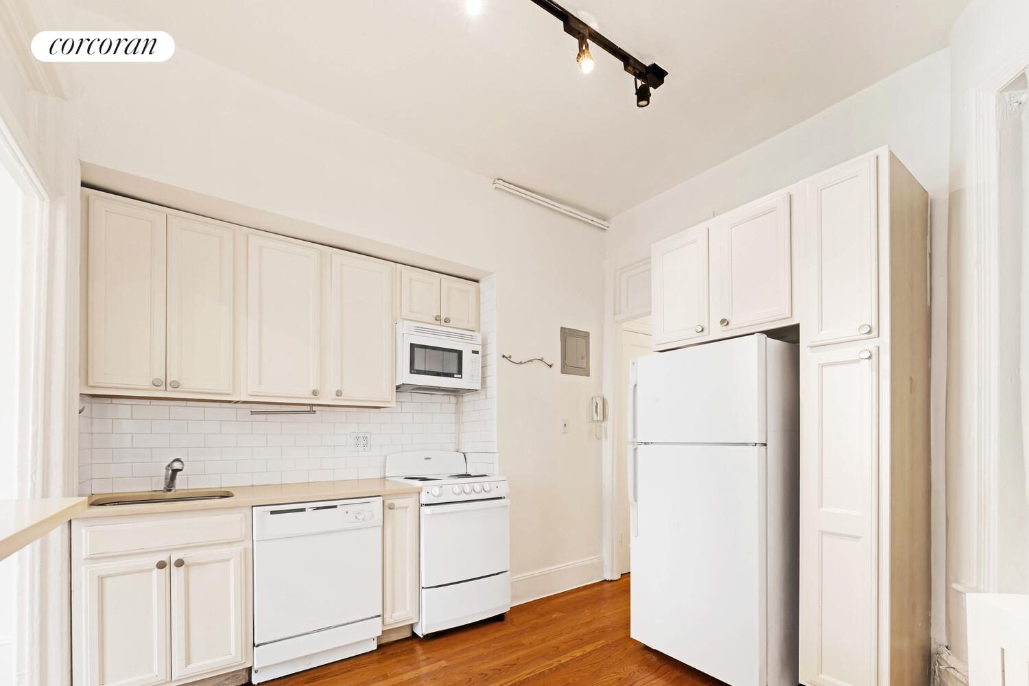 192 Bleecker Street, Unit 14 Manhattan, NY 10012 - Photo 13 of 17 a kitchen with white cabinets and white appliances