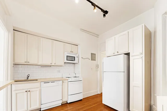 a kitchen with stainless steel appliances granite countertop white cabinets and window