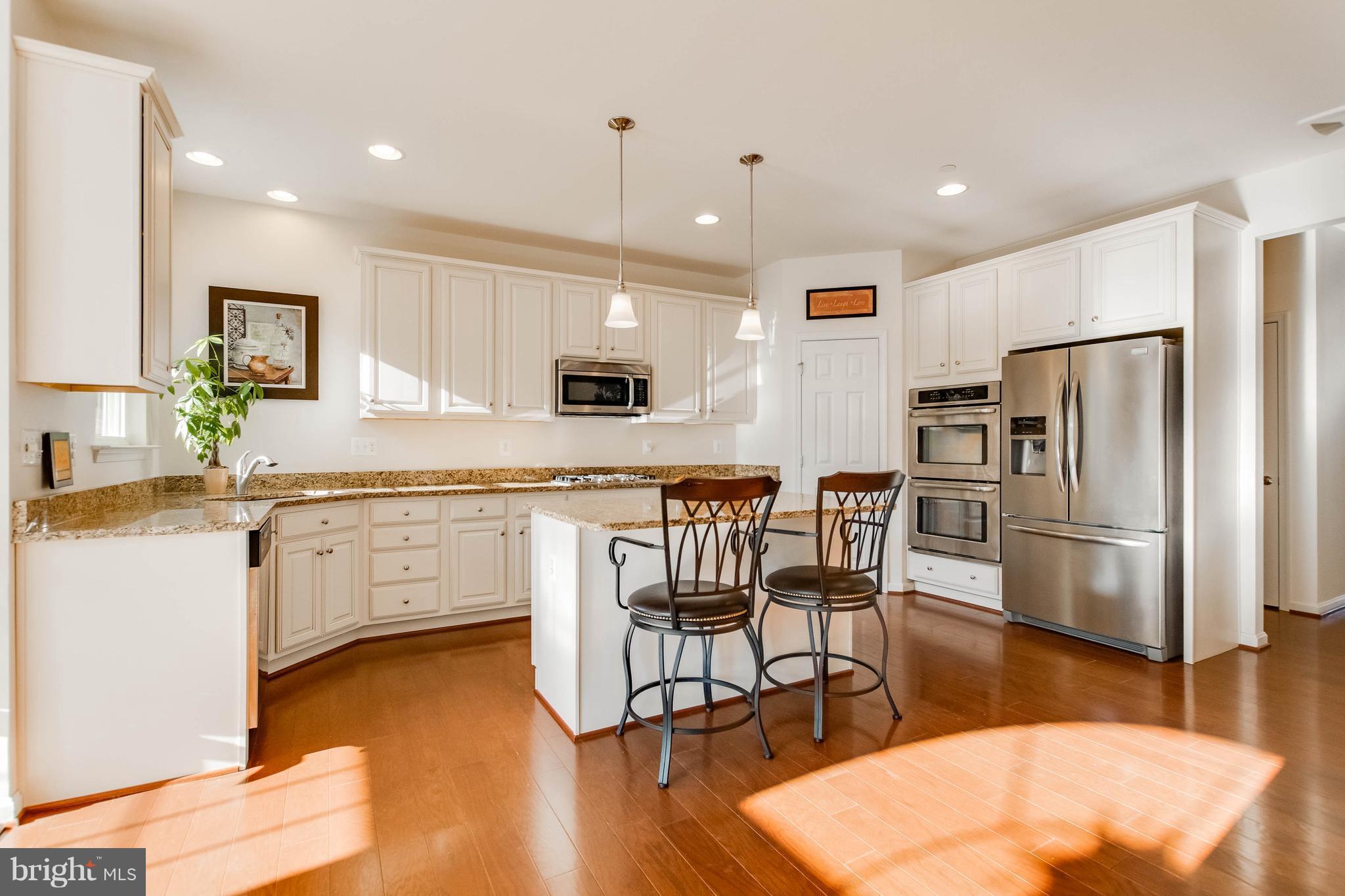 4117 Sweet Air Road Baldwin, MD 21013 - Photo 10 of 30 a kitchen with granite countertop a refrigerator a stove a sink a dining table and chairs with wooden floor