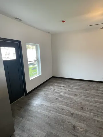 an empty room with wooden floor and windows