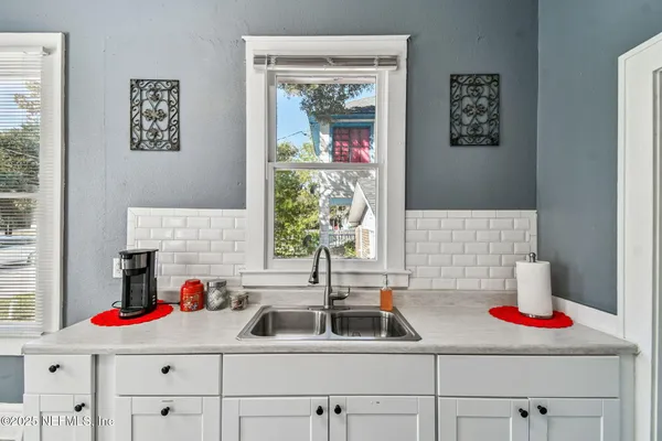 a kitchen with a sink wooden cabinets and a window